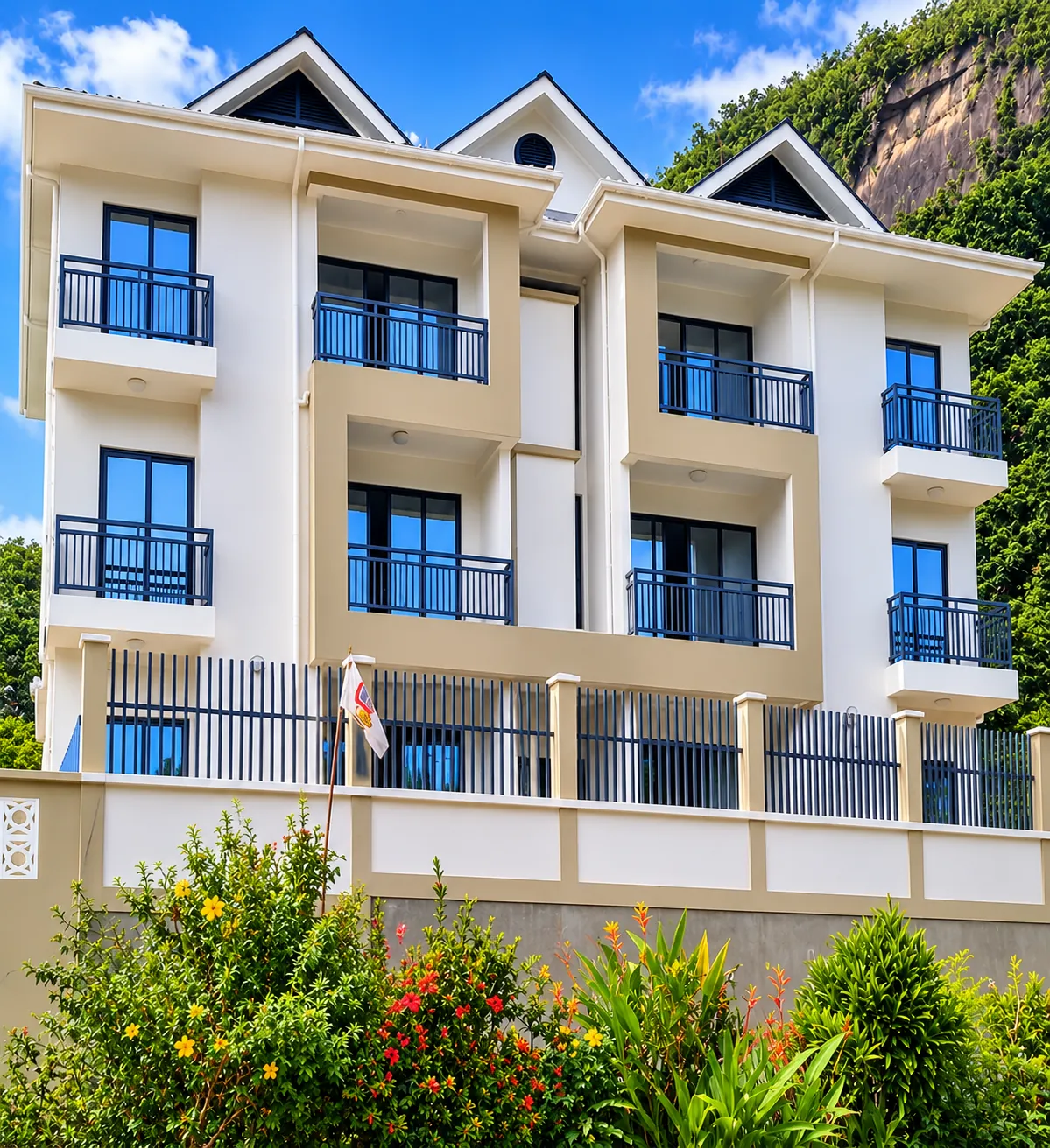 White residential apartment building with balconies set against a granite hillside