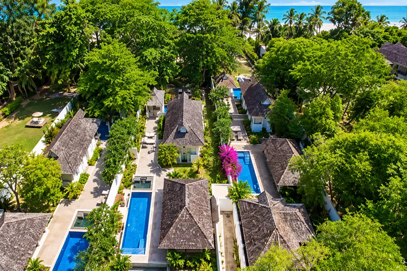 Aerial view of resort villas with private pools among trees